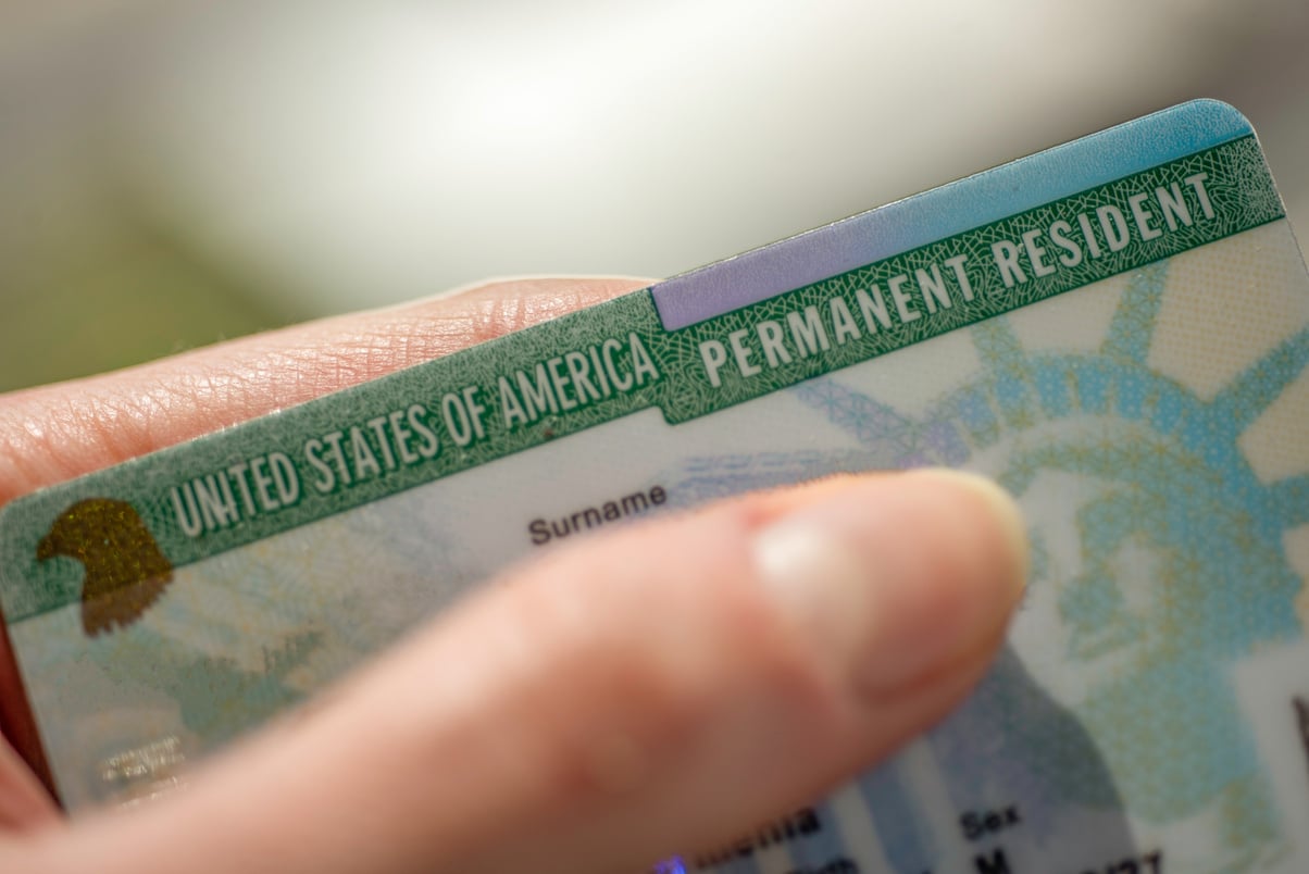 Close up view of Fragment of Permanent resident card (Green) card of USA on blurred background.